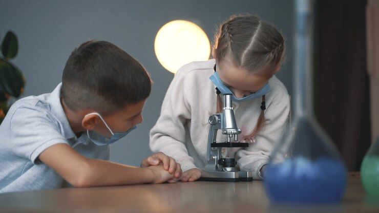 Crianças e ciência. Menino e menina com máscara facial usando um microscópio