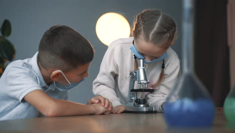 Kids-and-science.-Little-boy-and-girl-with-face-mask-using-a-microscope.