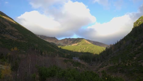 Beautiful-panoramic-pan-shot-of-a-mountain-valley-surrounded-by-high-altitude-peaks-in-High-Tatras,-Slovakia