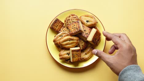 close-up of hand reaching for cookies on a yellow plate