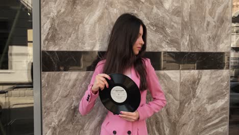 stylish brunette in pink posing with two discs on the street