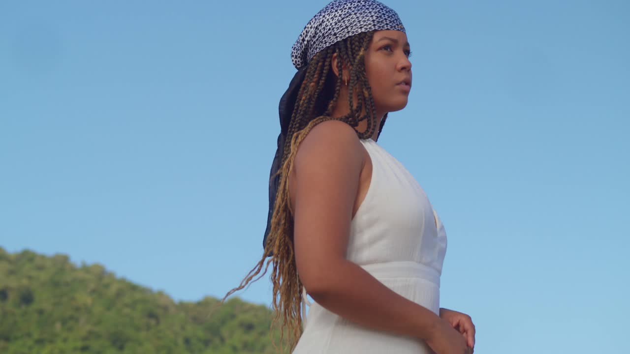 niña africana de piel clara mira el cielo azul claro en un día soleado en ropa de playa en la playa