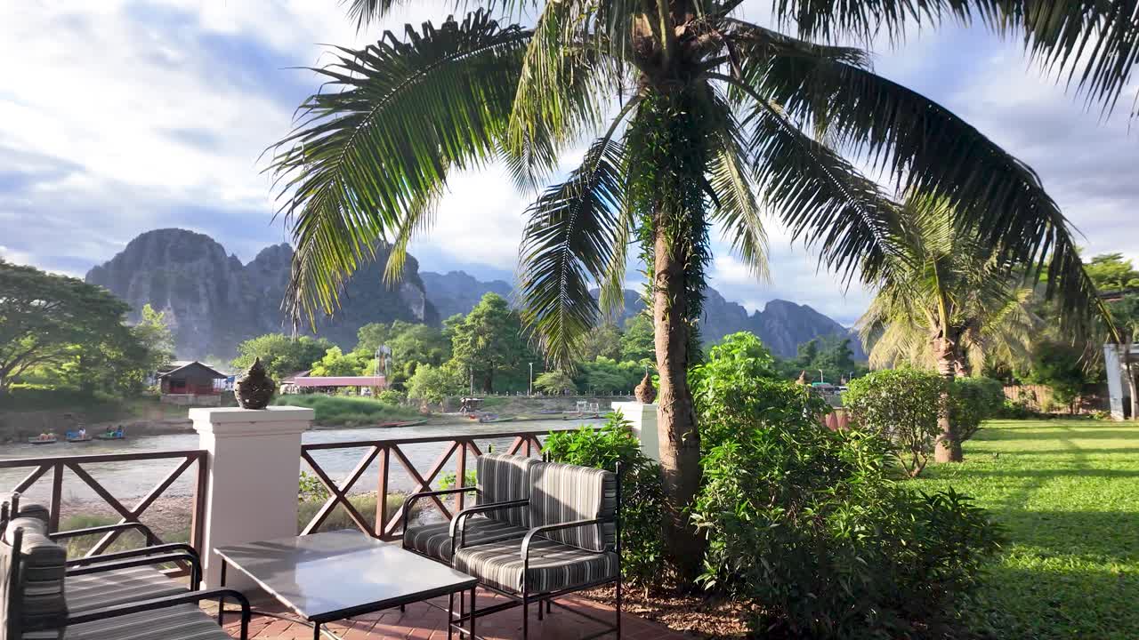 Vang Vieng resort patio overlooking Nam Song River and limestone mountains, offering a relaxing vacation