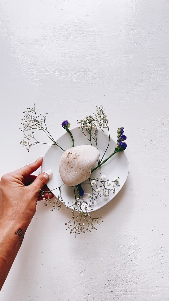 mano sosteniendo un plato con flores y una roca