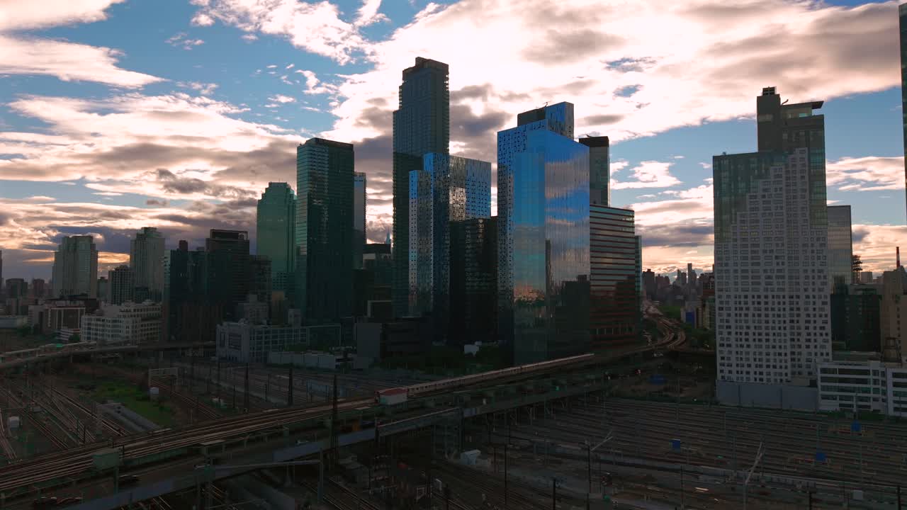 An aerial view of Long Island City, NY with skyscrapers in Queens. Taken during a cloudy evening over the Sunnyside Yard and Facility. The camera is stationary.