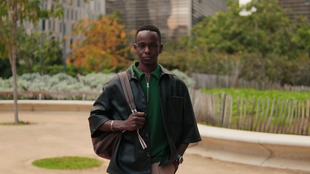 Young Black Man with Backpack Standing in Modern Urban Park