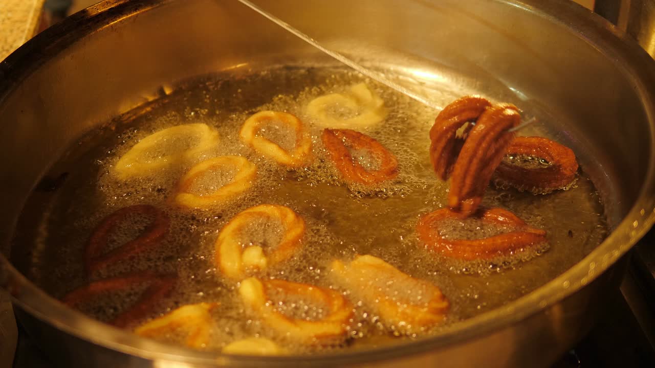 Close-up of donuts fried in boiling oil in the restaurant kitchen.