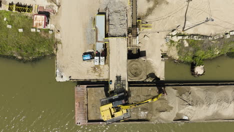 Clamshell-Bucket-Unloading-Sand-From-Barge-On-Arkansas-River-In-Van-Buren,-Arkansas