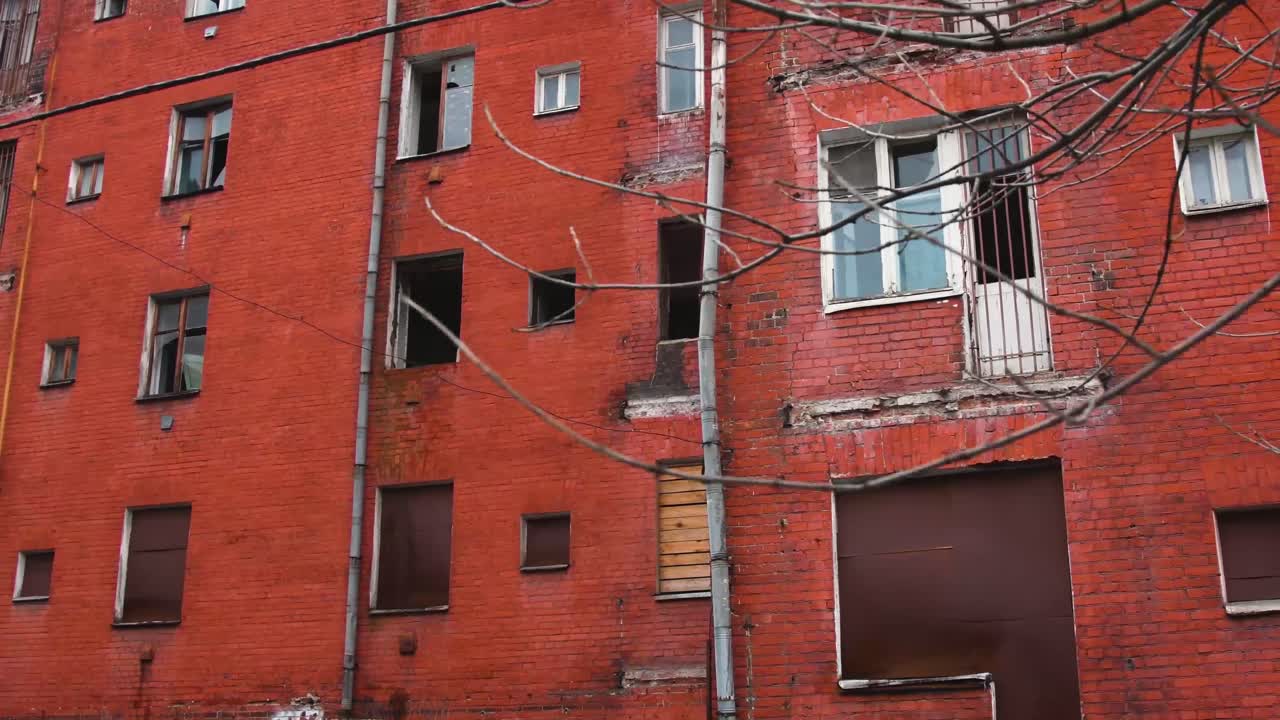 Camera sliding to the left, old and deserted Soviet red brick building, broken and dark windows