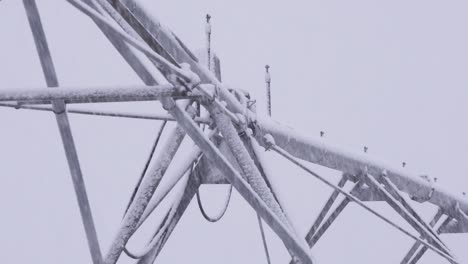 4K-close-up-shot-of-center-pivot-irrigation-equipment-in-an-open-farm-field,-during-a-blizzard-snowstorm