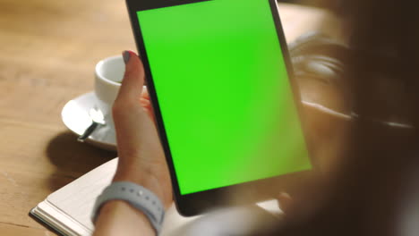 mujer sosteniendo una tableta con pantalla verde