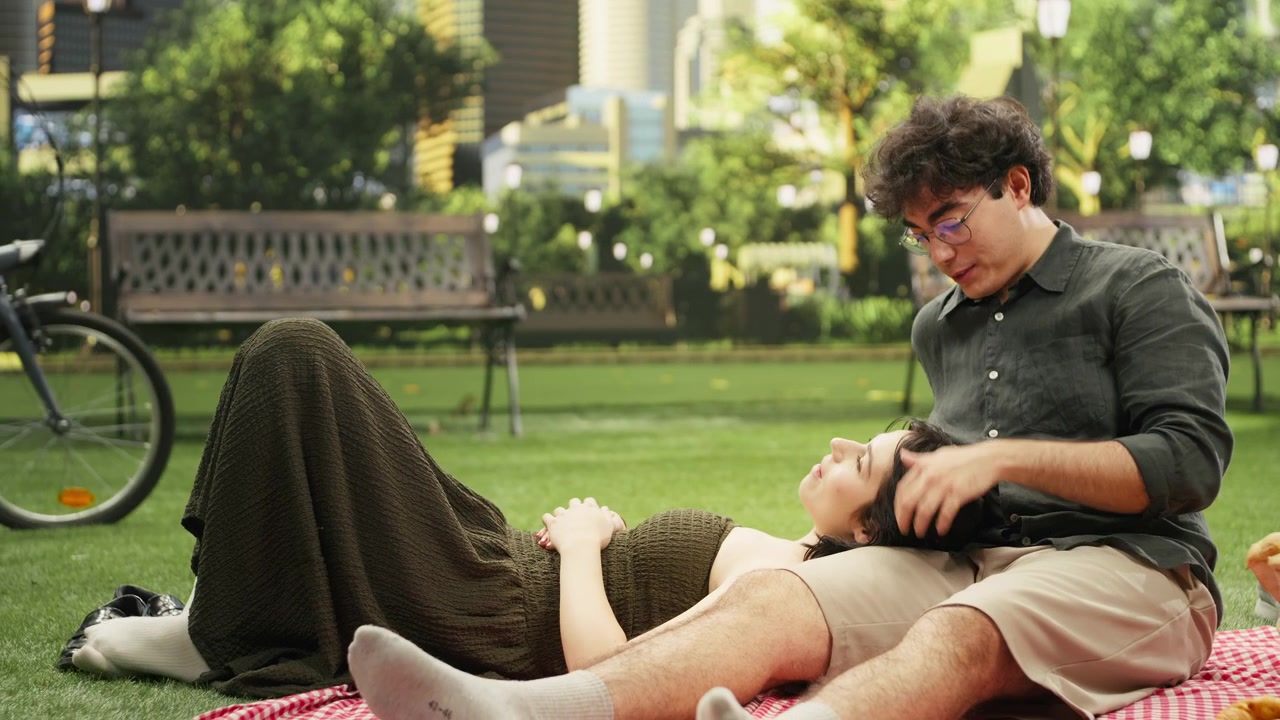 Fidanzato tiene delicatamente una giovane donna che riposa sulle sue ginocchia su una coperta da picnic.