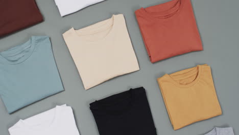 video of flat lay of t shirts with copy space on grey background