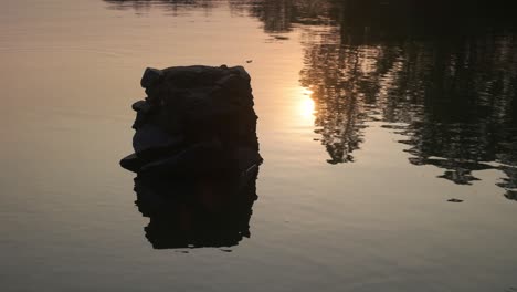 4k a rock sitting on a quiet afternoon lake