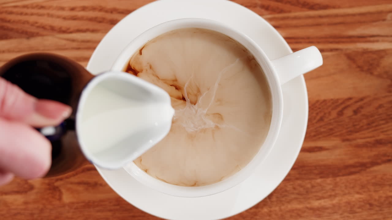 Pouring milk into a cup of coffee or tea