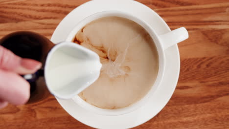 pouring milk into a cup of coffee or tea