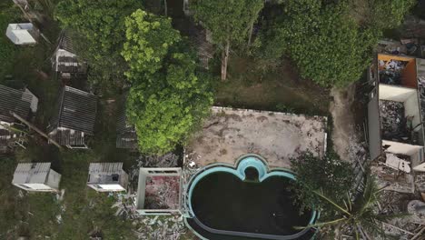 Ascending-Aerial-birds-eye-view-of-a-abandoned-and-derelict-beach-bungalow-tourist-resort-in-tropical-destination-due-to-the-effect-of-covid-on-global-travel-and-tourism