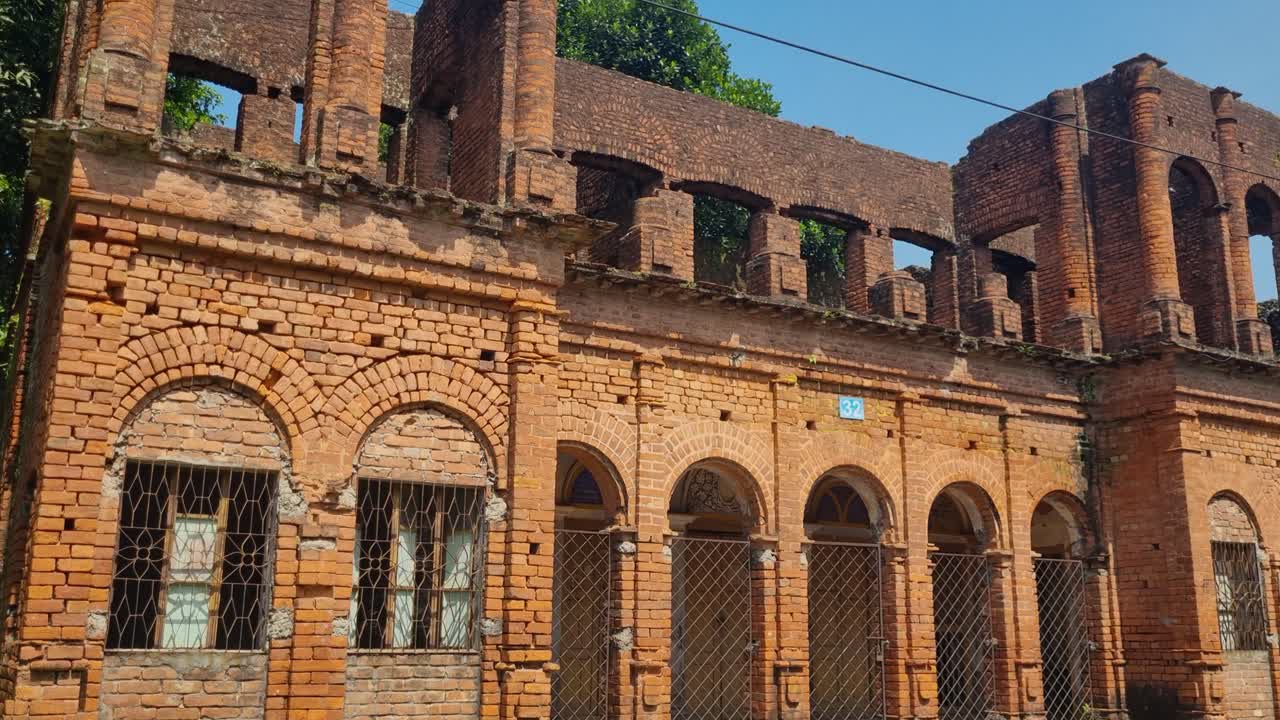 Weathered colonial mansion in Panam Nagar, Bangladesh, its exposed bricks and faded arches glowing in the warm autumn sunlight, echoing traces of a vanished era