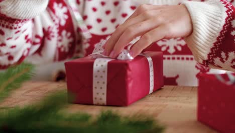 Cerca-De-Las-Manos-De-La-Niña-Decorando-El-Regalo-De-Navidad.