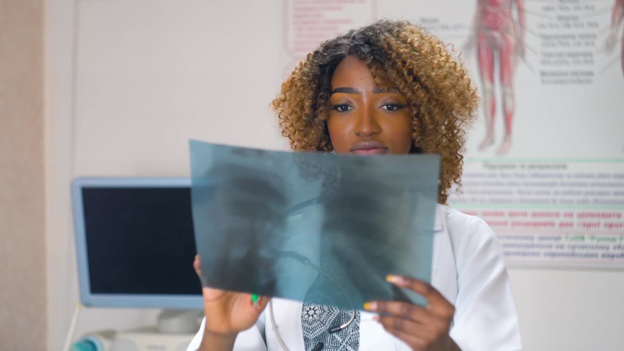 una médica afroamericana examina las radiografías de los pulmones en una clínica. un médico examina las rayas x de los pulmóns de un paciente con coronavirus