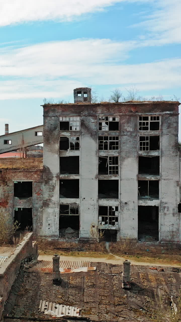 Aerial view of an old factory ruin and broken windows. Old industrial building for demolition. Vertical video