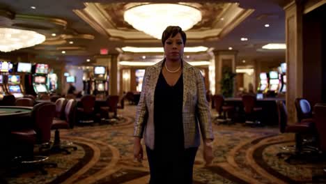 a confident woman walking through a casino, exuding grace and authority amidst the glitzy environment filled with slot machines and gaming tables