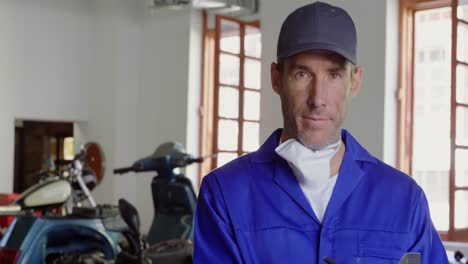 mecánico masculino escribiendo en el clipboard en un garaje de reparación de motocicletas 4k