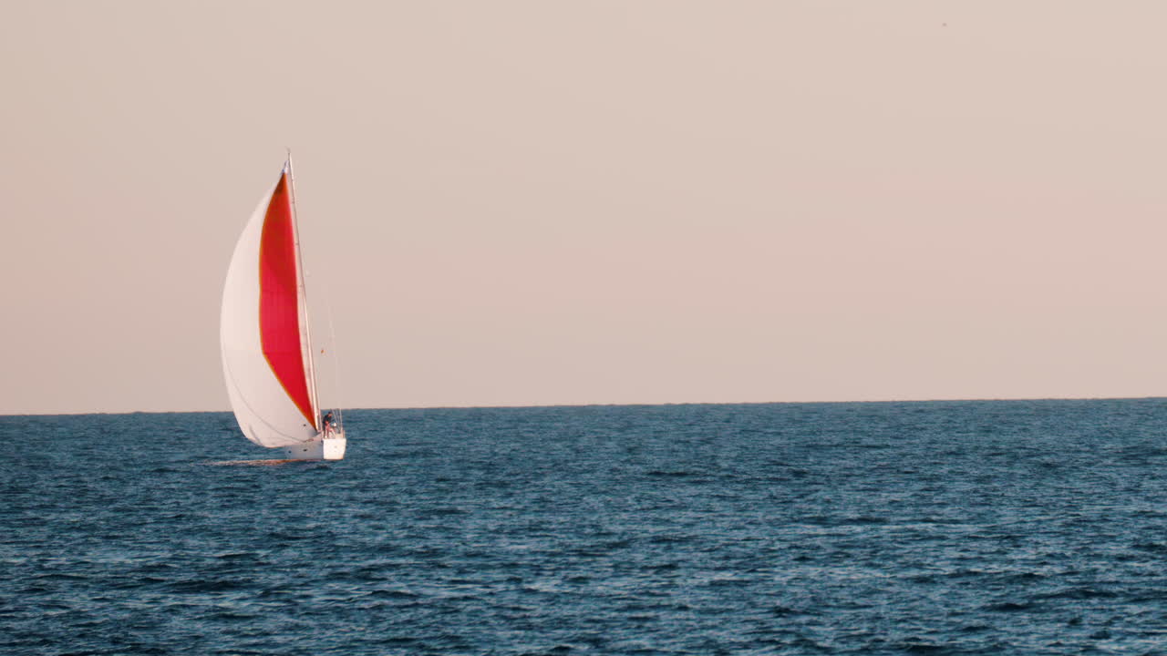 Small ship with a red sails moving on the sea in Golfe-Juan, France