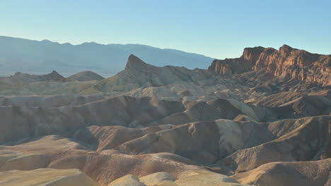 the hilly landscape of zabriskie point in death valley is illuminated by the setting sun, zoom out shot