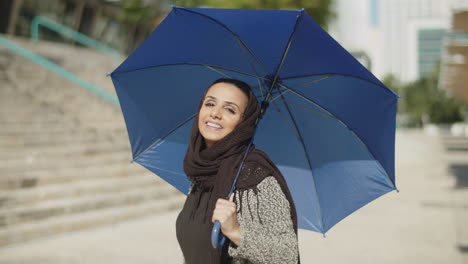 young muslim woman in hijab posing with umbrella.