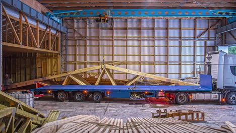 at a warehouse loading prefabricated roof trusses on a truck bed for transporting - time lapse