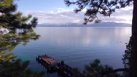 pretty panning shot of the shores of lake tahoe nevada with sierras and pier