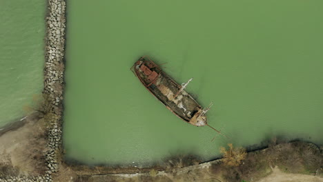 Rostiges-Rotes-Schiffswrack-Steckte-Im-Seichten-Grünen-Wasser-Fest