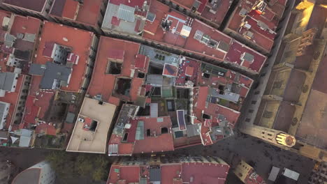 Top-down-panning-footage-of-houses-and-their-roofs-in-urban-borough.-Narrow-aisles-between-blocks-of-buildings.-Barcelona,-Spain