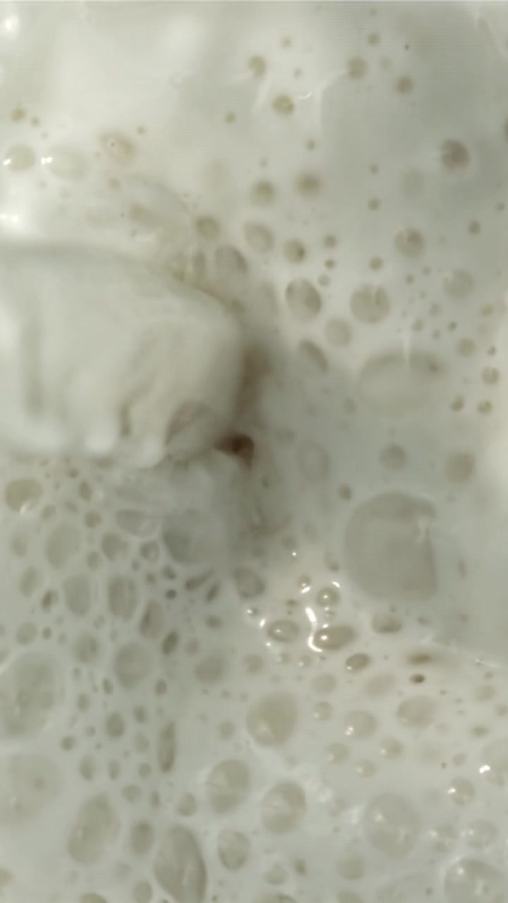 Primo piano di liquido bianco schiumoso che viene mescolato