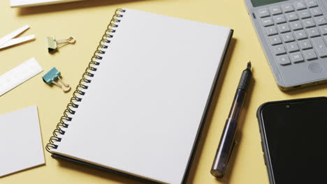 close-up di notebook, smartphone e cancelleria scolastica su sfondo giallo, in slow motion