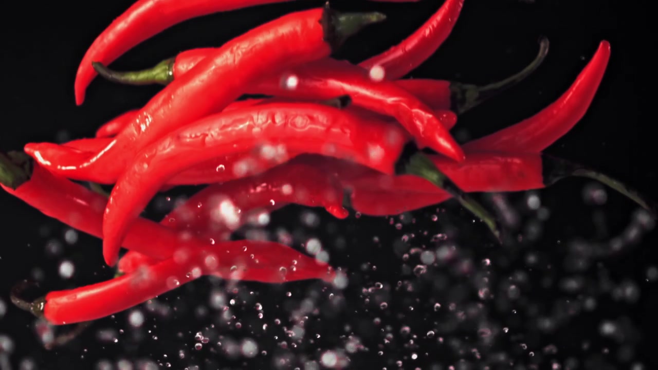 Red Chili Peppers Floating in Slow Motion with Water Droplets