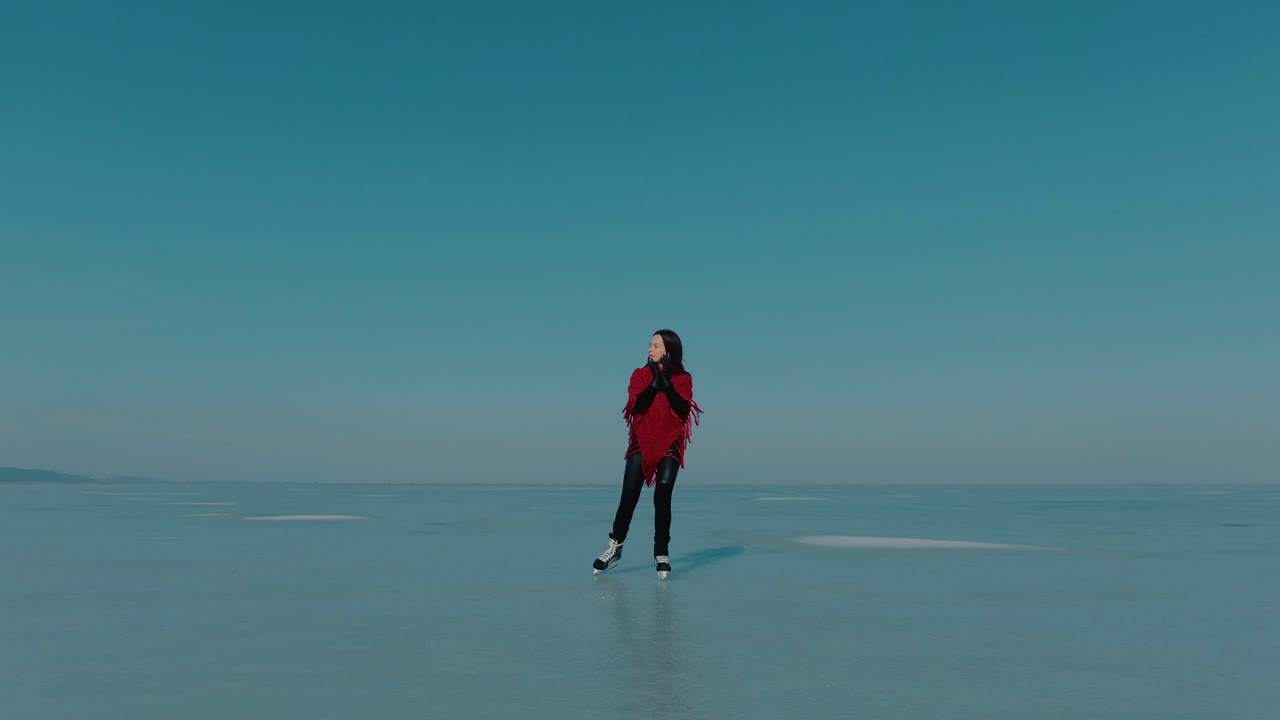 seguimiento de la toma frontal de una niña patinando sobre hielo en un lago congelado con un chal rojo, en un día claro y soleado, momentos serenos