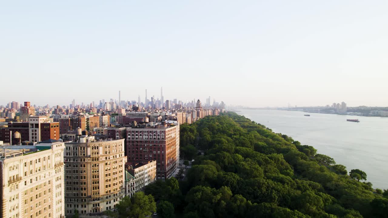 Drone shot along NYC's west side featuring apartments, park space and Hudson River