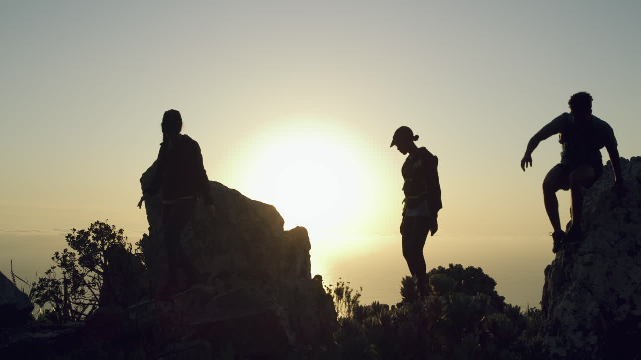 silueta de excursionistas en la cima de la montaña al amanecer