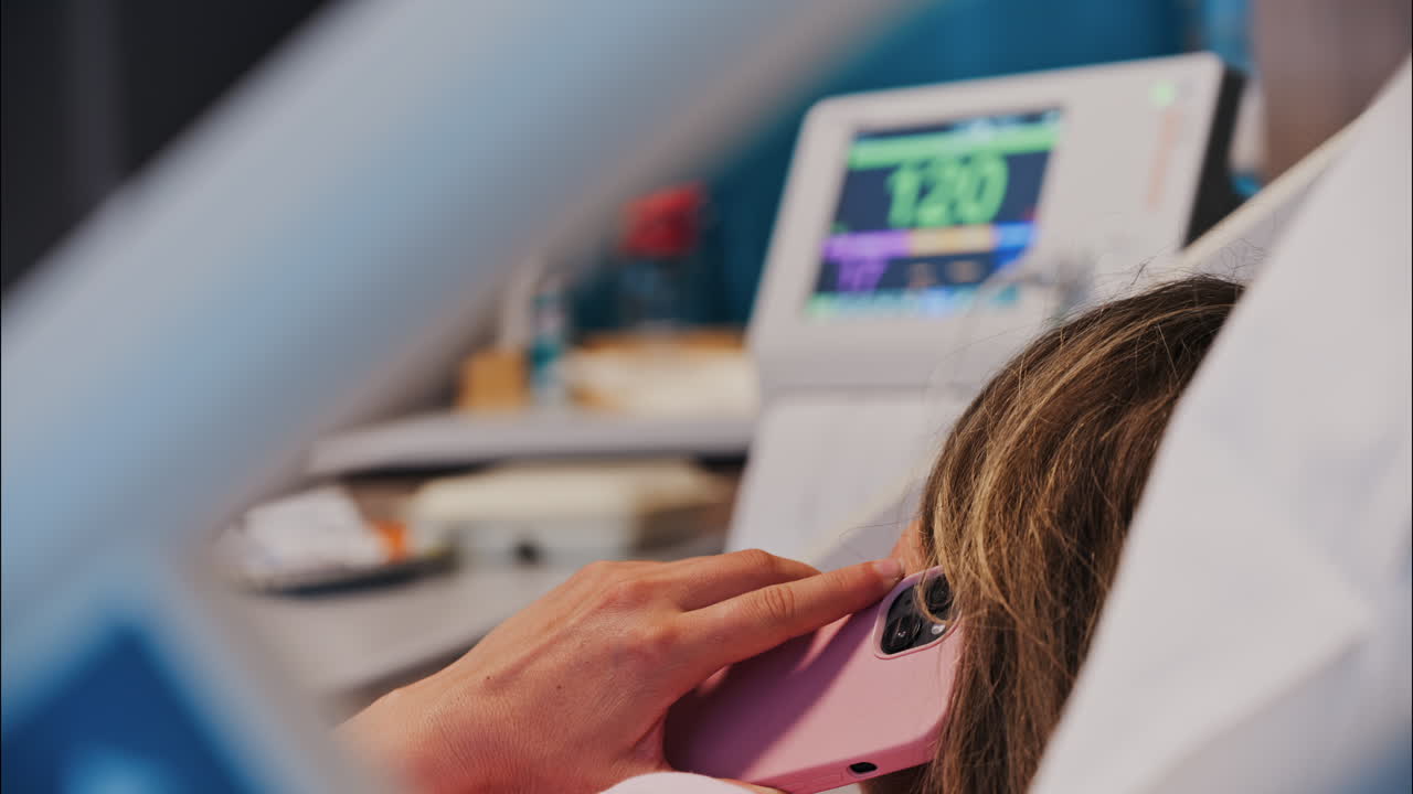 Pregnant woman talking on her phone while doing a prenatal check-up at the doctor's office