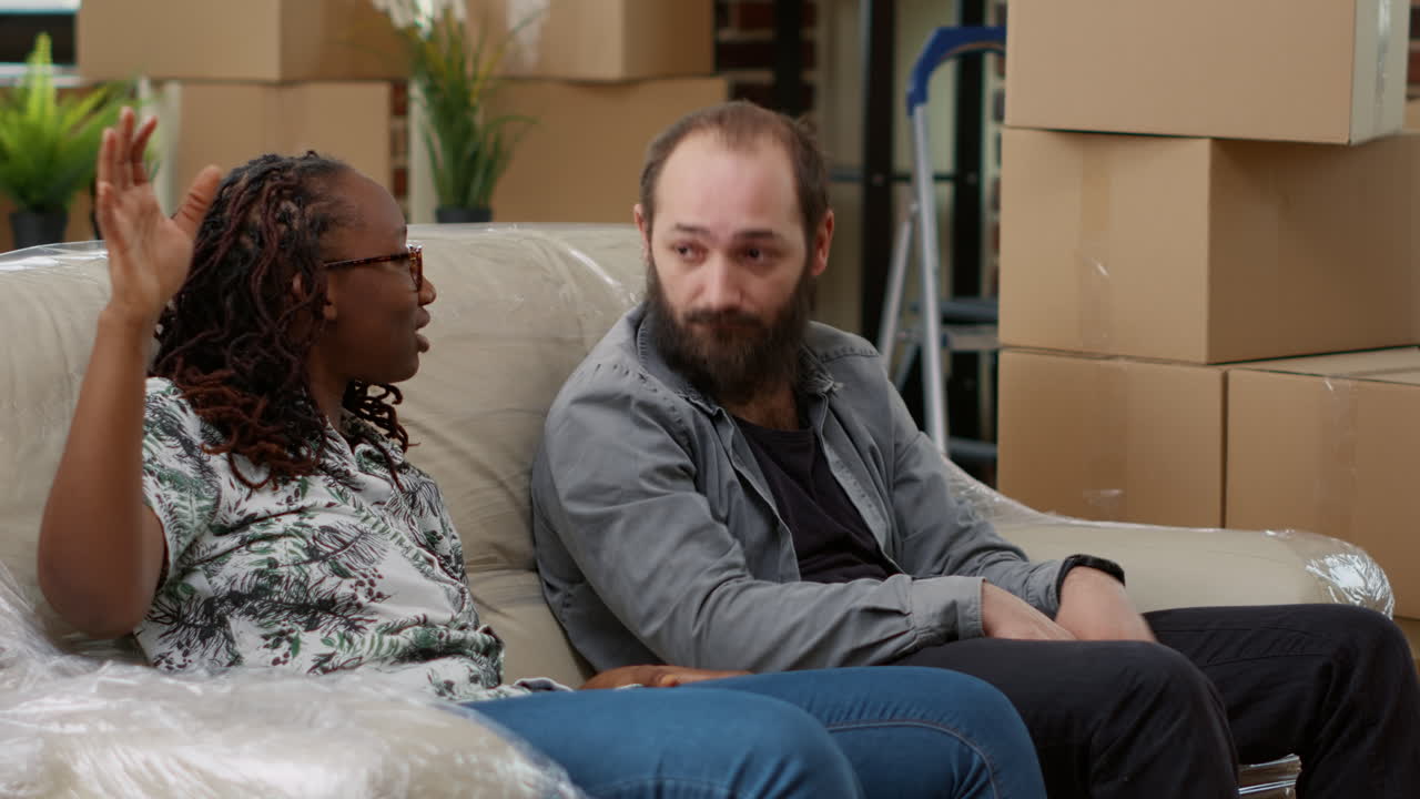 Exhausted life partners taking break after moving boxes in apartment