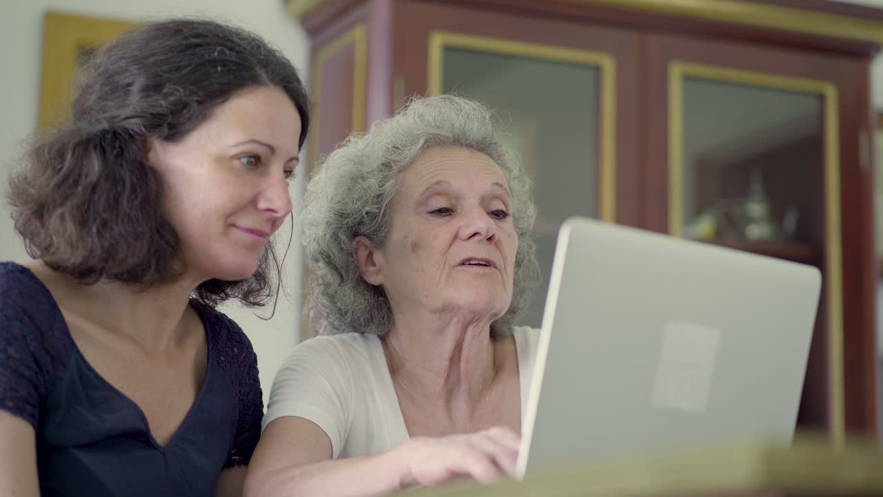 mujeres maduras sonrientes usando una computadora portátil en casa.