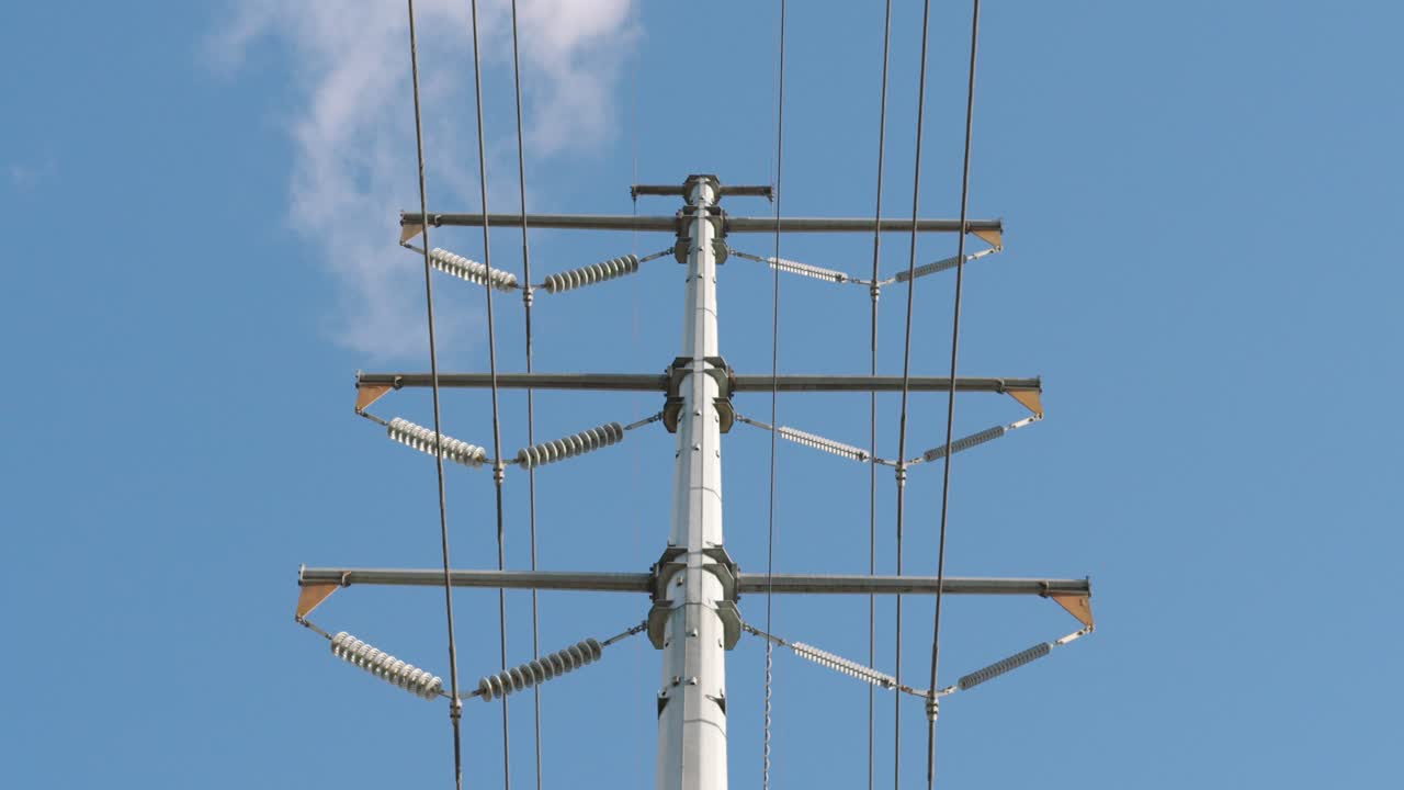 Low angle view of utility pole with power lines under a sunny but partly cloudy day