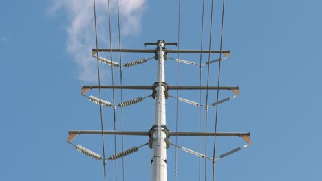 low angle view of utility pole with power lines under a sunny but partly cloudy day