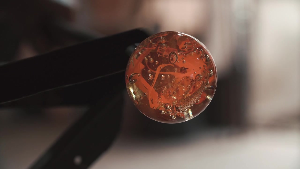 Primo piano di una sfera di vetro arancione rotante con bolle e motivi a spirale