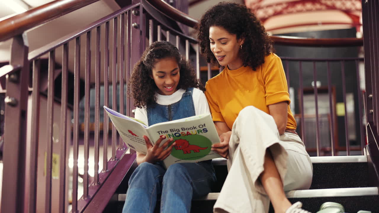 Mutter und Tochter lesen ein Dinosaurierbuch auf der Treppe