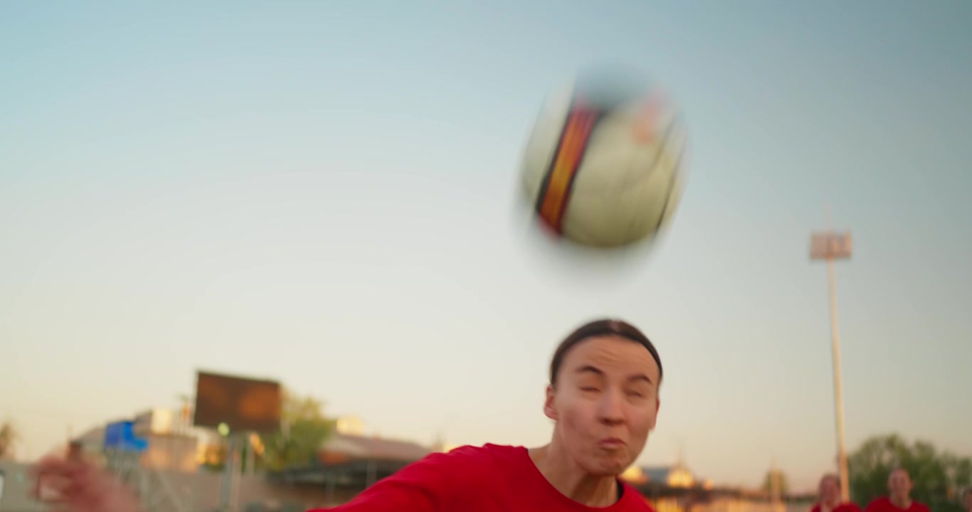 Young Female Soccer Player Heading a Ball During Practice on a Green Field