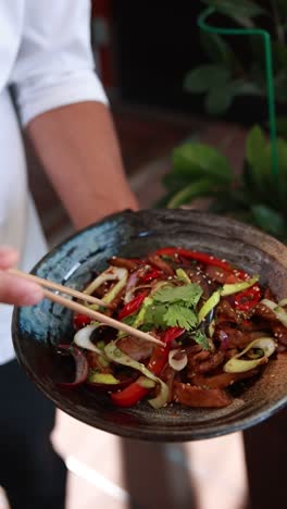 chef serving stir-fried vegetables and meat