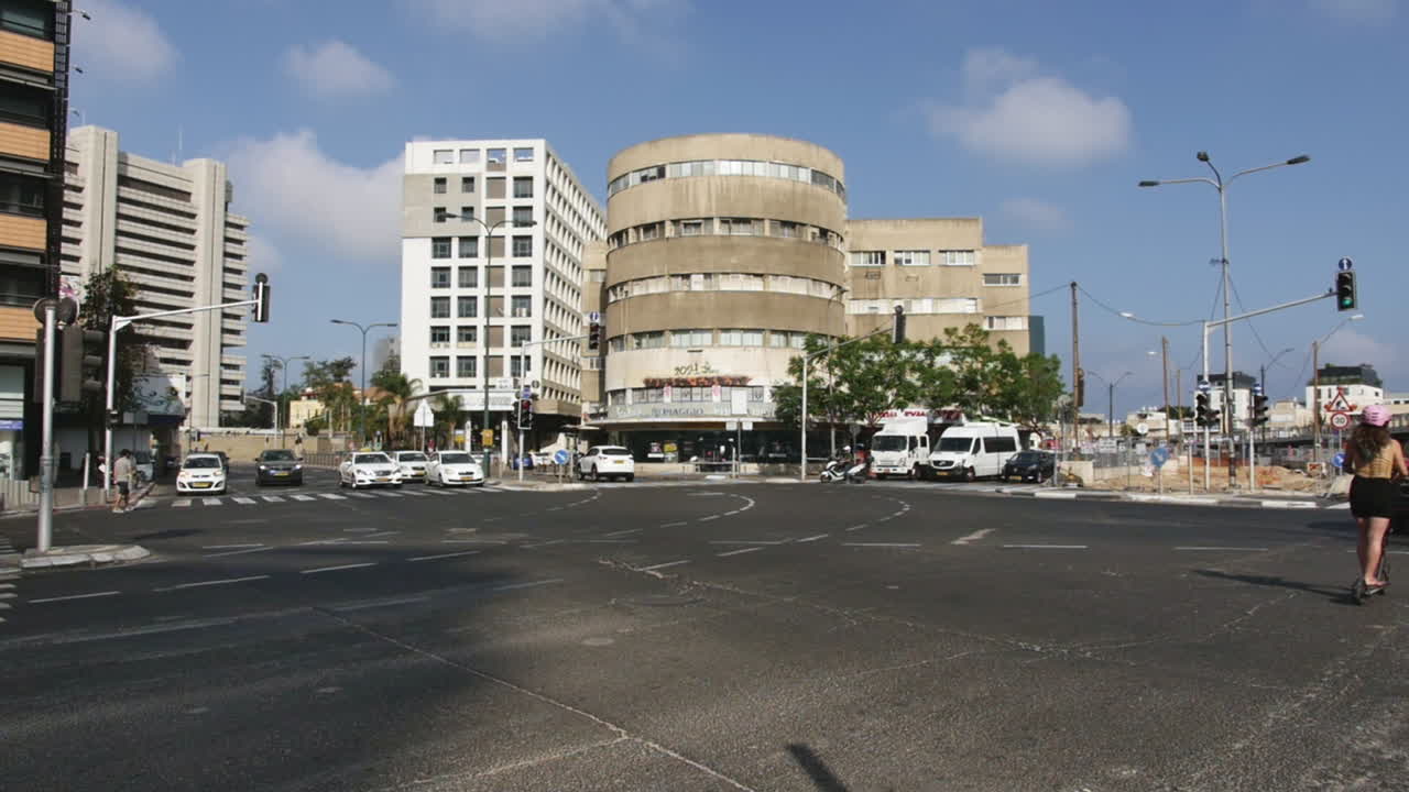 분홍색 헬멧을 쓴 스쿠터를 타고 도시 거리를 누비는 젊은 여성